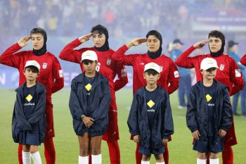 Iran's players salute during the national anthem before the AFC Women's Asian Cup Australia 2026 football match between Iran and Philippines in Gold Coast on March 8, 2026. The son of the late shah urged Canberra on March 9 to protect the Iranian women's football team, who were branded "wartime traitors" after refusing to sing the national anthem while playing in Australia. (Photo by AFP) / -- IMAGE RESTRICTED TO EDITORIAL USE - STRICTLY NO COMMERCIAL USE --