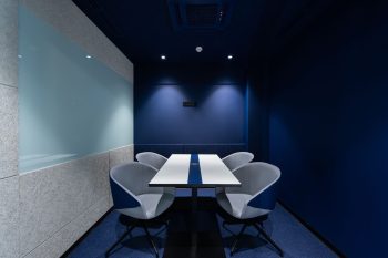 Blue conference room with four chairs and a white table