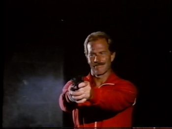 Richard Harrison aiming a pistol in a red jacket, in a scene from one of his action films.