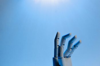 A robotic hand against a blue background illustrates artificial intelligence