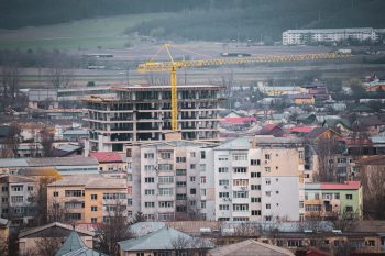 View of a city construction site with a prominent tower crane and surrounding buildings