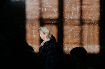 A woman in a plaid shirt walking through an indoor space with striking shadows on the wall