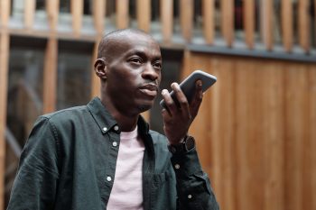Illustrative photo of a person speaking into a smartphone, relating to multilingual AI voice interfaces