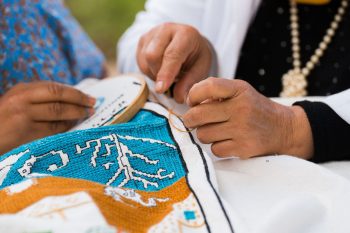 Hands embroidering a colorful traditional fabric