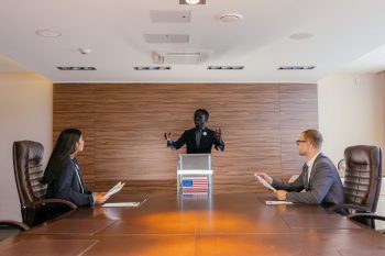 People seated in a conference room as one person speaks at a podium